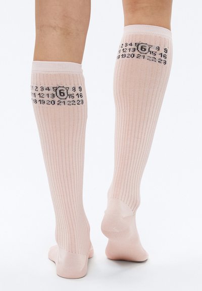 Ružové ponožky po kolená s rebrovanou textúrou, na zadnej strane čierne čísla zobrazujúce vzor pripomínajúci kalendár. Hladký materiál.