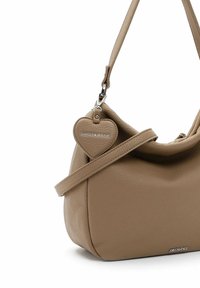 Sac à main en cuir beige avec une forme arrondie, doté d'une étiquette en forme de cœur détachable et d'une longue anse.