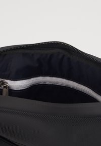Borsa nera con apertura a zip, caratterizzata da un'esterno liscio e una fodera in tessuto scuro. L'interno presenta un dettaglio in zip bianco.