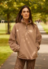 Beige zip-hals sweatshirt gemaakt van zachte fleece, met elastische boorden en zijzakken, gecombineerd met leggings met luipaardprint.