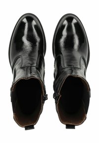 Bottines en cuir noir avec une finition brillante, à bouts ronds et avec des fermetures éclair discrètes sur les côtés extérieurs. L'intérieur présente une doublure beige.