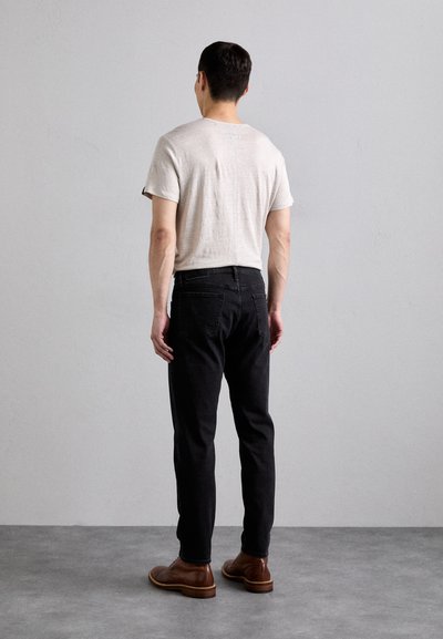 Camisa de manga corta en gris claro para hombre combinada con jeans negros y zapatos de cuero marrón. Diseño sencillo, forma ajustada y textura suave.