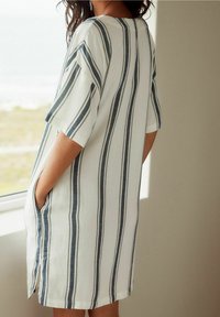 Vestido de rayas en blanco y azul marino, con mangas cortas, un corte holgado, bolsillos laterales y largo por debajo de la rodilla. Tejido suave y ligero.