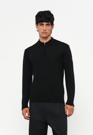 Zwarte polo met lange mouwen en een ritskraag. Gebreide textuur, slim fit ontwerp en geribde manchetten. Logopatch op de linkermouw.