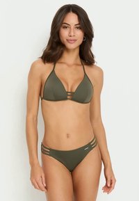 Bikini vert olive avec un haut triangulaire et des découpes latérales. Tissu texturé, design minimaliste, bretelles réglables et logo en métal.