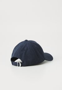 Mørkeblå kordfløjls baseballcap med buet skygge, justerbar rem bagpå, og tekstureret stof med lodrette ribber.