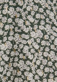 Bloemstof met kleine witte bloemen en metallic gouden accenten op een donkergroene achtergrond. Zacht, gestructureerd materiaal met een fijn patroon.