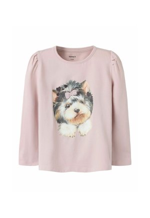 Chemise rose clair à manches longues avec des épaules bouffantes, avec le visage imprimé d'un petit chien portant un nœud rose et entouré de cœurs noirs.