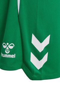 Grønne sportsshorts med hvidt Hummel-logo og to hvide nedadvendte chevrons på stoffet.