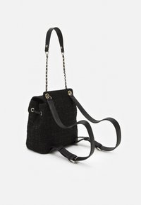 Sac noir texturé avec une apparence tissée, doté d'une chaîne et d'une bandoulière en cuir noir, de deux poignées et d'accents en métal.