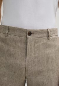 Beige linnen broek met een knoopsluiting, riemlussen en zijzakken, vervaardigd uit een textuurstof met een subtiel geweven patroon.