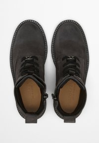 Dunkelgraue Wildleder-Schnürstiefel mit schwarzen Sohlen, seitlichen Reißverschlüssen und braunen Innensohlen mit Markenprägung, von oben auf weißem Hintergrund betrachtet.