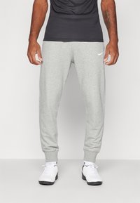 Graue Sweatpants aus Baumwollmischgewebe mit tapered Design, elastischen Bündchen und einem weißen Nike-Logo auf dem linken Oberschenkel.