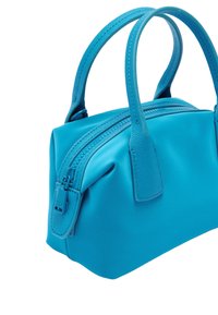 Turkusowa torba na ramię o wyraźnej formie, gładki materiał syntetyczny, podwójne uchwyty u góry i zamek błyskawiczny z fakturowanymi akcentami.