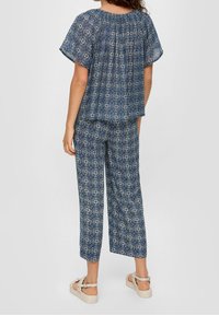 Haut à motif bleu avec manches courtes et pantalon ample assorti, en tissu léger, présentant un motif géométrique et un col froncé.