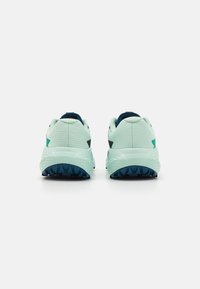 Baskets de sport vert clair avec une tige texturée, ornées d'accents bleu foncé et d'une semelle noire robuste pour une meilleure adhérence.