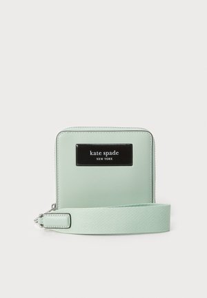 Carteira verde menta com um exterior de couro suave, placa de logotipo preta e uma alça de tecido mint destacável. Fecho de zíper na parte superior.