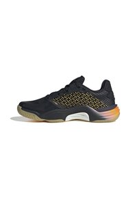 Zapatilla deportiva negra con parte superior de malla texturizada, acentos dorados y suela de goma que presenta un degradado multicolor en el talón.