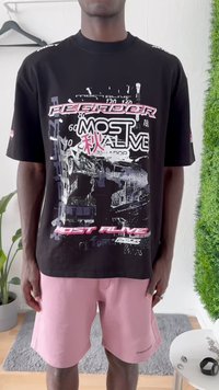 Black graphic t-shirt featuring bold text and contrasting colors, paired with light pink shorts and a casual fit.