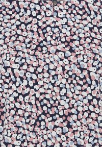Marineblaue Stoffbluse mit verstreutem Blumenmuster in Pink, Weiß und Hellblau, mit geknöpftem Ausschnitt und strukturierter Oberfläche.