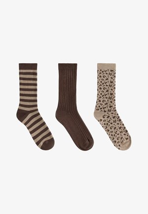 Trei șosete în tonuri maronii: cu dungi, solide cu rețea și cu imprimeu de leopard, aranjate una lângă alta pe un fundal alb.