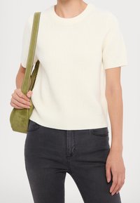 Maglione a coste di colore crema a maniche corte, con scollatura rotonda, abbinato a jeans grigi scuri e una borsa a tracolla in suede verde oliva.