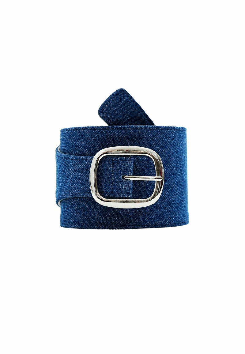 Ceinture en denim bleu roulée avec une boucle carrée argentée sur fond blanc.