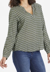 Grønt mønstret bluse med et diamantdesign i hvid. Letvægtsstof, V-hals og lange ærmer med en afslappet pasform.