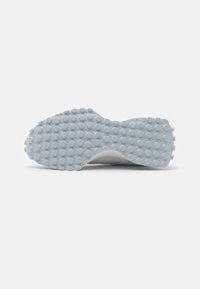 Shoe sole with a textured light gray rubber surface featuring circular protrusions for grip, curved shape, and a smooth edge.