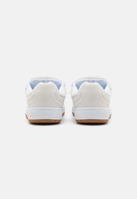 Adidași albi cu un superior din suede texturat și plasă, guler căptușit și o talpă din cauciuc gumos cu o formă rotundă.