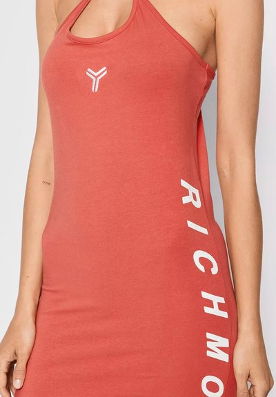 Donna che indossa un vestito senza maniche di colore corallo con un piccolo logo bianco sul petto e la scritta "RICHMOND" stampata verticalmente sul lato.
