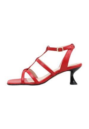 Sandalia roja con tiras, puntera cuadrada, tacón curvado negro de altura media y correa con hebilla en el tobillo sobre fondo blanco.