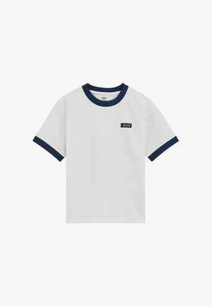 Camiseta blanca de manga corta con cuello y puños en azul marino, con un pequeño parche azul marino con texto blanco en el pecho izquierdo.