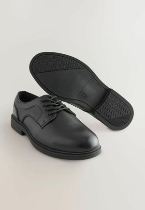 Melnas ādas kleitu kurpes ar gludu apdari, ar auklām un teksturētu gumijas zoli. Iezīmējas ar noapaļotu purngalu un smalkiem šuvju pārsteigumiem.