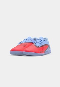 Czerwono-niebieskie buty sportowe mają teksturowaną cholewkę, zapięcie na sznurówki oraz gumową podeszwę z wzorem falistym. Logo Nike na boku.