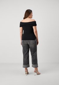 Μαύρη κορυφή χωρίς ώμους με συγκεντρωμένο ύφασμα, συνδυασμένη με γκρίζα φθαρμένα παντελόνια σε άλφα γραμμή και ασημένια σανδάλια με τακούνι.