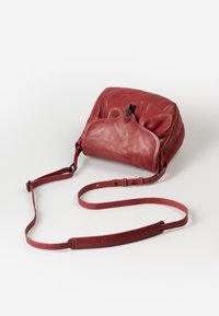 Rote Leder-Schultertasche mit einer weichen, strukturierten Oberfläche. Verfügt über einen oberen Verschluss mit einem schwarzen Zugband und einem verstellbaren Trageriemen.