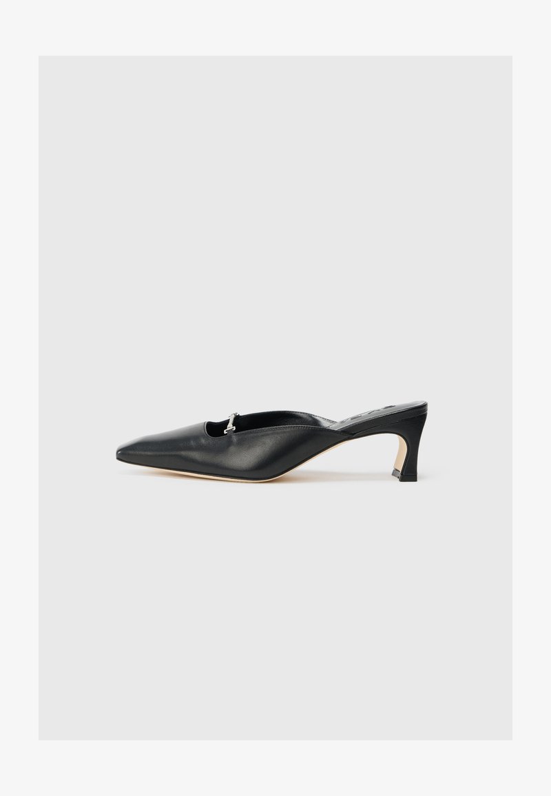 Scarpa slingback in pelle nera con punta affusolata, tacco basso e un dettaglio in acciaio inox all'apertura. Texture liscia, design minimalista.