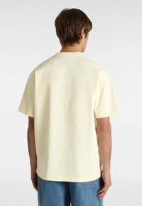 Gelbes Baumwoll-T-Shirt mit kurzen Ä sleeves und einem runden Halsausschnitt. Der Stoff scheint weich mit einer glatten Textur und einem lockeren Schnitt zu sein.