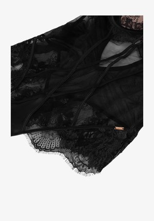 Vêtement en dentelle noire transparente présentant des motifs floraux complexes, des textures contrastées, une fermeture éclair et de délicates bords effilochés.