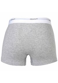 Boxer da uomo grigi in cotone con cintura bianca su cui è stampato in nero il nome del marchio "GANT". Texture liscia, senza ulteriori motivi.