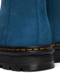 Botas de tornozelo em camurça azul com superfície texturizada, costura amarela em contraste e sola de borracha preta resistente.