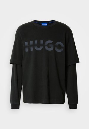 Černé oversized tričko s kulatým výstřihem. Na hrudi se nachází výrazné matné černé logo "HUGO". Měkký bavlněný materiál, dlouhé rukávy.