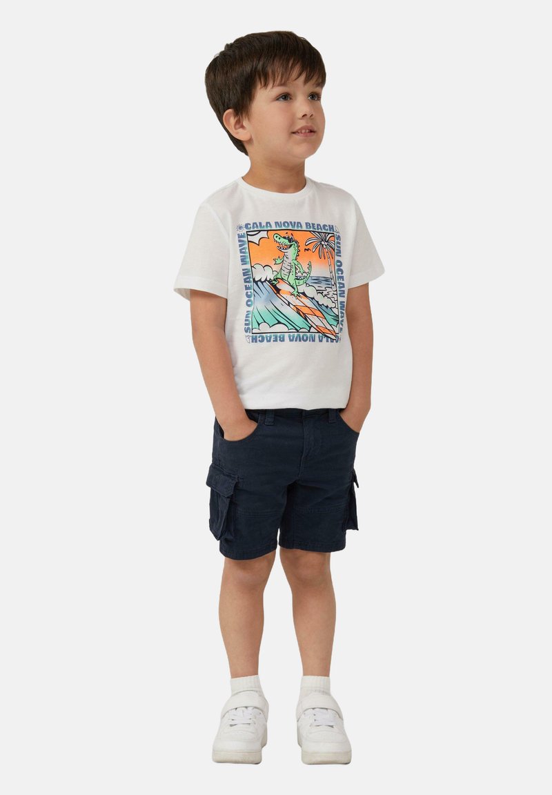 Witte katoenen T-shirt met een kleurrijke dinosaurustekening, gecombineerd met marineblauwe cargoshorts en witte sneakers, met een luxe textuur.