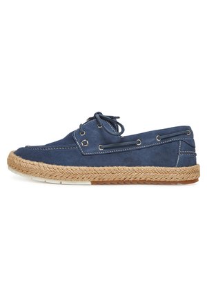 Scarpa da barca in camoscio blu navy con cuciture bianche, chiusura frontale con lacci e suola intrecciata in corda beige con base in gomma antiscivolo.