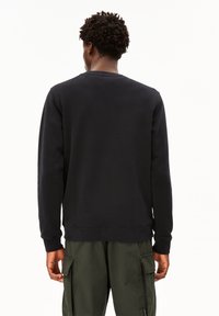 Felpa nera a collo rotondo con maniche lunghe, polsini a coste e finitura testurizzata, abbinata a pantaloni cargo verdi oliva.