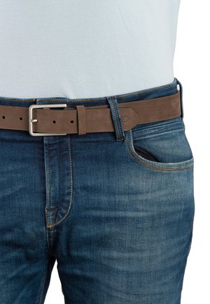 Ceinture en cuir brun avec une boucle rectangulaire en argent, portée sur un jean bleu avec des détails de couture visibles et une légère décoloration.