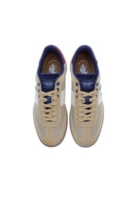 Béžové tenisky s hladkým svrškem, bílou částí, námořnickými akcenty a kulatými očky. Obsahují béžové tkaničky a polstrovanou stélku.
