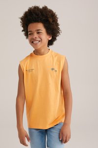 Oranžová bezrukávová tričko z bavlny s okrúhlym výstrihom, zelenou grafikou palmy a svetlomodrými džínsami. Hladká štruktúra.