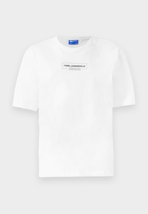 Vit bomullströja med korta ärmar, med en rektangulär svart logotyp med texten "KARL LAGERFELD JEANS" centrerad på bröstet.